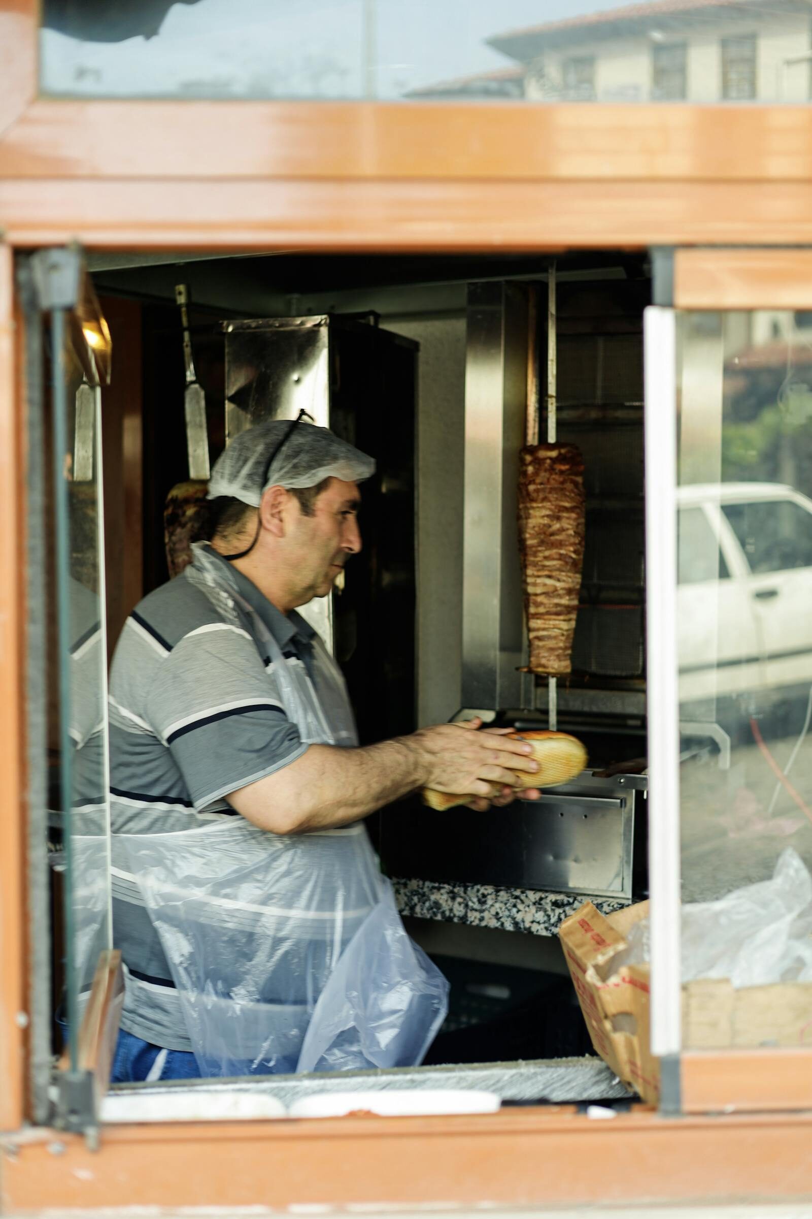 Hands wrapping a sandwich at a busy Moroccan street-food counter, the sort of counter action you see at Mister Cook Hay El Mohammadi Agadir
