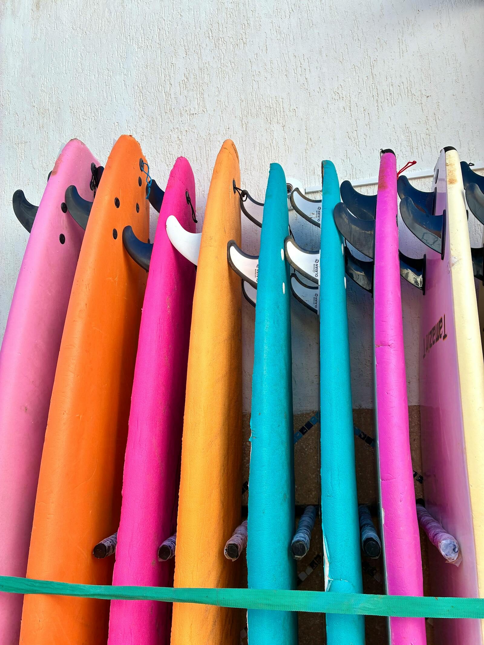 Surfboards stacked on a wooden rack outside a Moroccan surf school