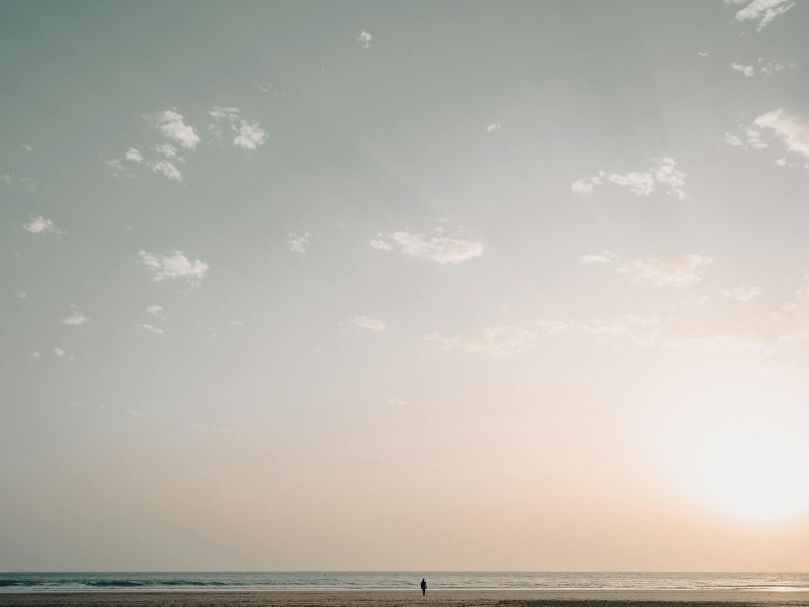 Quiet Moroccan beach at dawn with a solitary walker on the sand